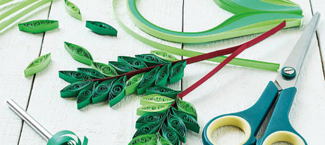 Create rowan leaves in the technique of quilling for autumn design. Strips of paper, scissors, twigs with leaves on a white wooden table. Selective focus